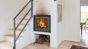 A staircase leading to a fireplace with a fire burning, a door to an outdoor area, and a framed picture on the wall. - 5 Person Holiday Home in Knebel (Knebel)