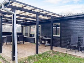 Un patio techado al aire libre con una parrilla, zona de estar y vistas del paisaje circundante.