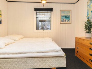 Quarto com cama, janela, penteadeira e um quadro na parede.