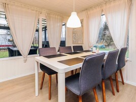 Comedor con mesa blanca, seis sillas y una lámpara colgante.