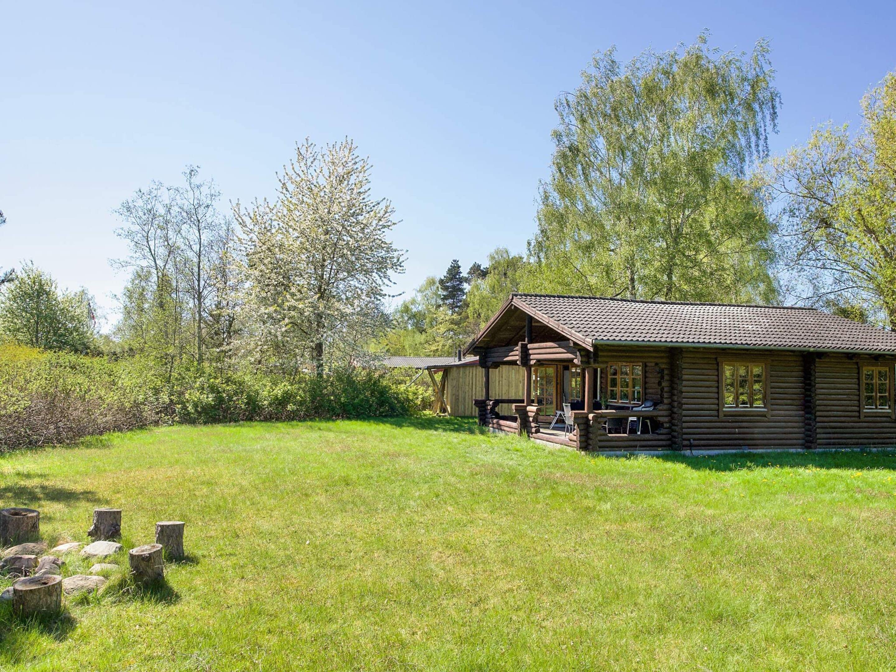 Une cabane en bois avec une véranda et une pelouse devant.