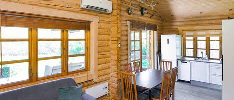 Ein Blockhaus-Interieur mit Essbereich, Küche und einer Couch.