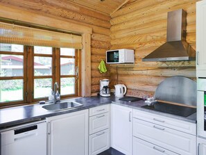 A kitchen with wooden walls, a stainless steel sink, a built-in microwave, and a range hood. - 6 Person Holiday Home in Eskebjerg (Eskebjerg)