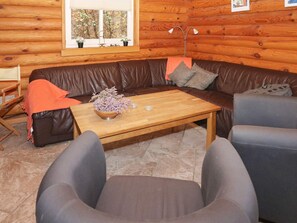 A cozy log cabin interior with a brown leather sofa, a wooden coffee table, and two grey armchairs. - 4 Star Holiday Home in Hadsund (Hadsund)