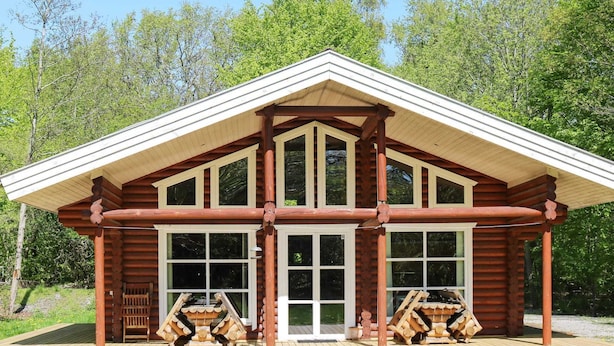 A log cabin with a gabled roof, large windows, and a wooden deck. - 4 Star Holiday Home in Hadsund (Hadsund)