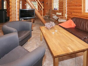 A log cabin interior with a wooden table, two sofas, a television, and a fireplace. - 4 Star Holiday Home in Hadsund (Hadsund)