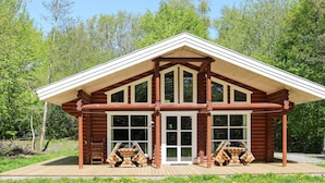 A log cabin with a pitched roof, large windows, and a wooden deck. - 4 Star Holiday Home in Hadsund (Hadsund)
