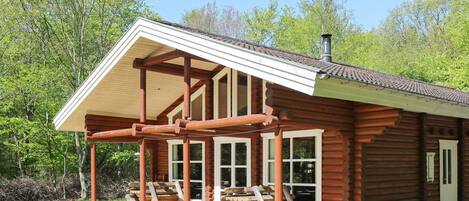A log cabin with a wooden deck and a covered porch.