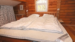 A wooden cabin bedroom with a bed, a window, and a small table. - 4 Star Holiday Home in Hadsund (Hadsund)
