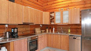 A kitchen with wooden cabinets, a stainless steel refrigerator, a dishwasher, and a coffee maker. - 4 Star Holiday Home in Hadsund (Hadsund)