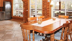 A wooden cabin interior with a dining table, chairs, a refrigerator, and large windows. - 4 Star Holiday Home in Hadsund (Hadsund)