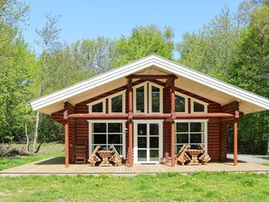 A log cabin with a pitched roof, large windows, and a deck area. - 4 Star Holiday Home in Hadsund (Hadsund)