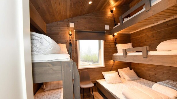 Une petite pièce de style cabane en bois, avec des lits superposés et un petit bureau.