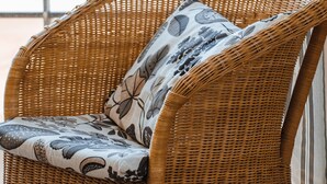 A wicker chair with floral cushions by a window with a view of the ocean. - Diamond Beach A3 - pleasant 2-bedroom apartment with sea view (De Haan)