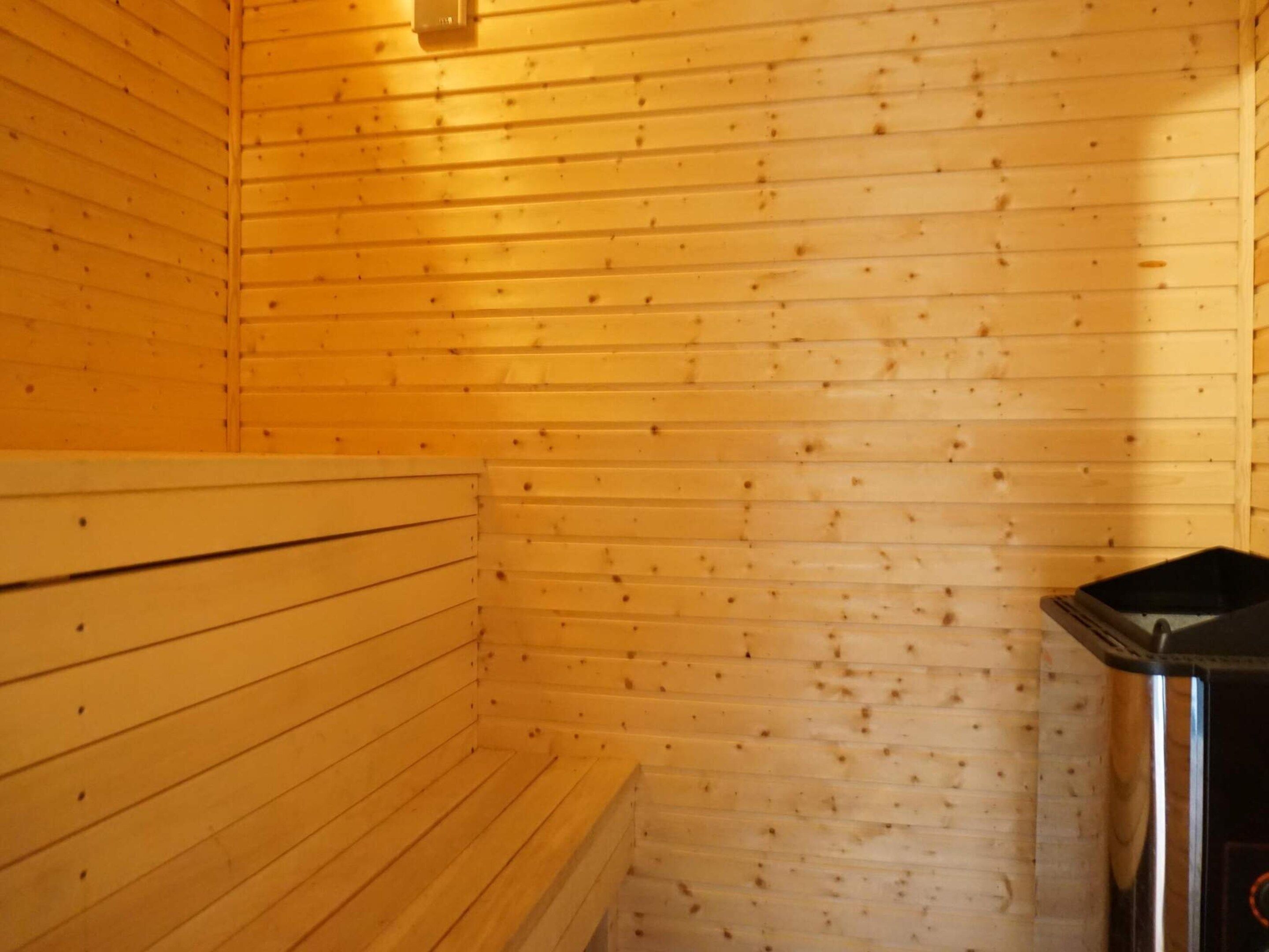 Un sauna avec des murs en bois et un banc.