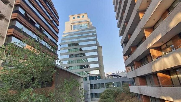 A modern building with a pool surrounded by greenery.