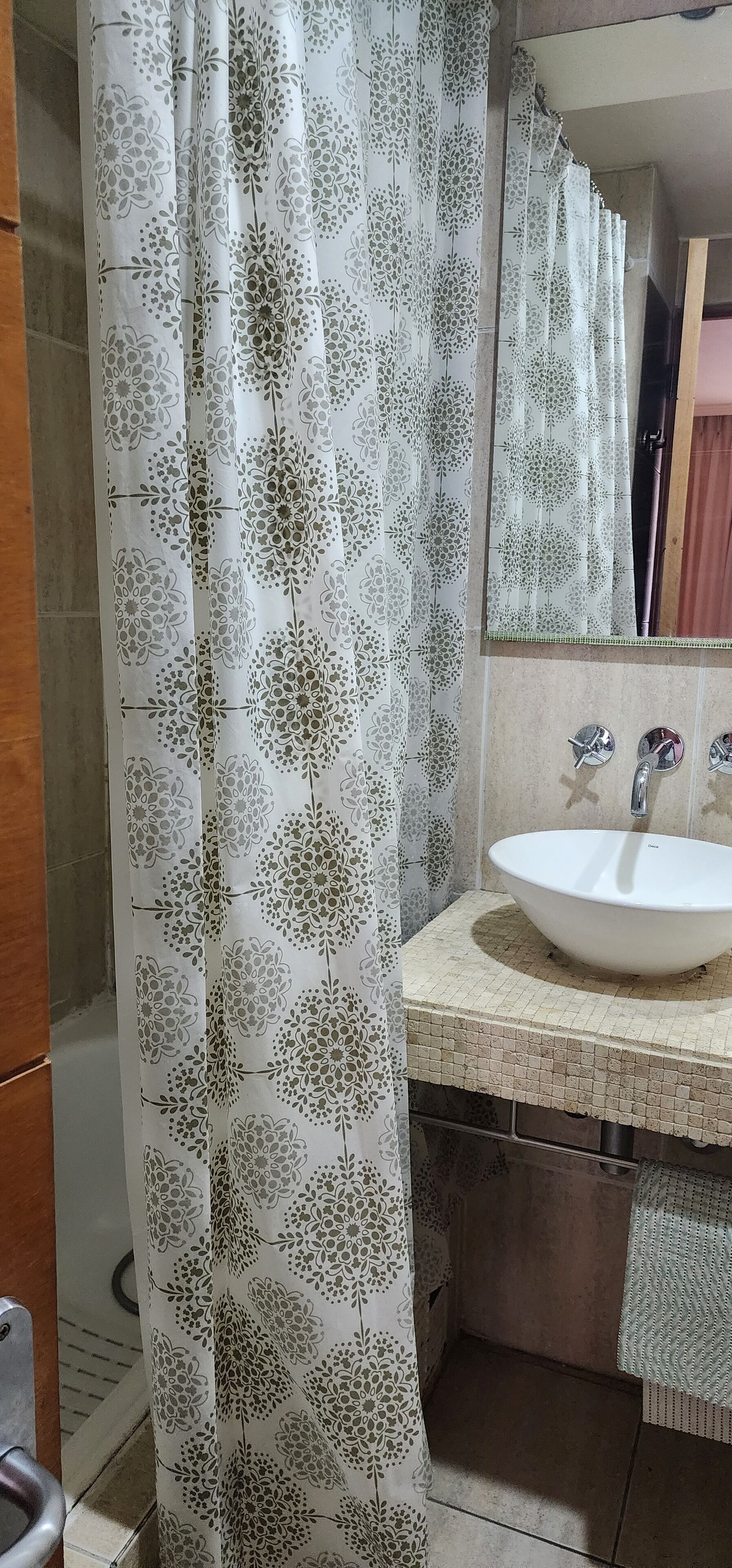 A bathroom with a white sink, a mirror, and a shower curtain with a floral pattern.