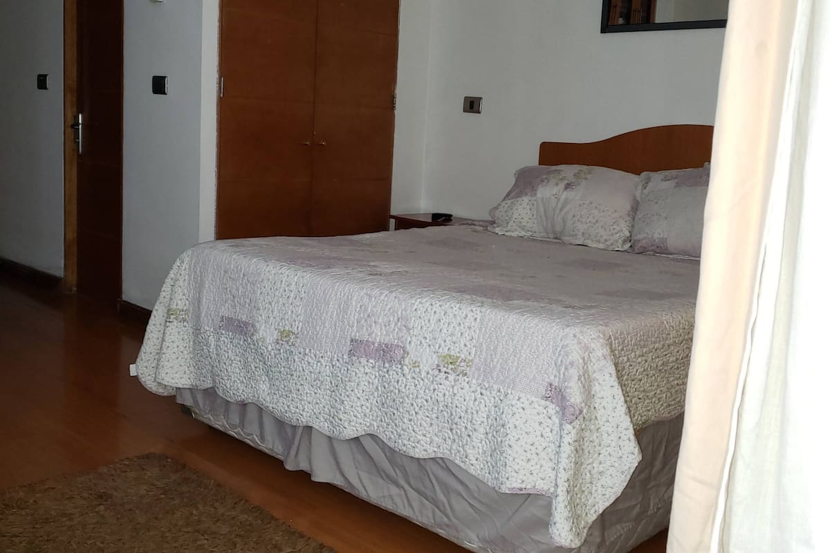 Un dormitorio con cama, armario de madera y una mesita de noche.