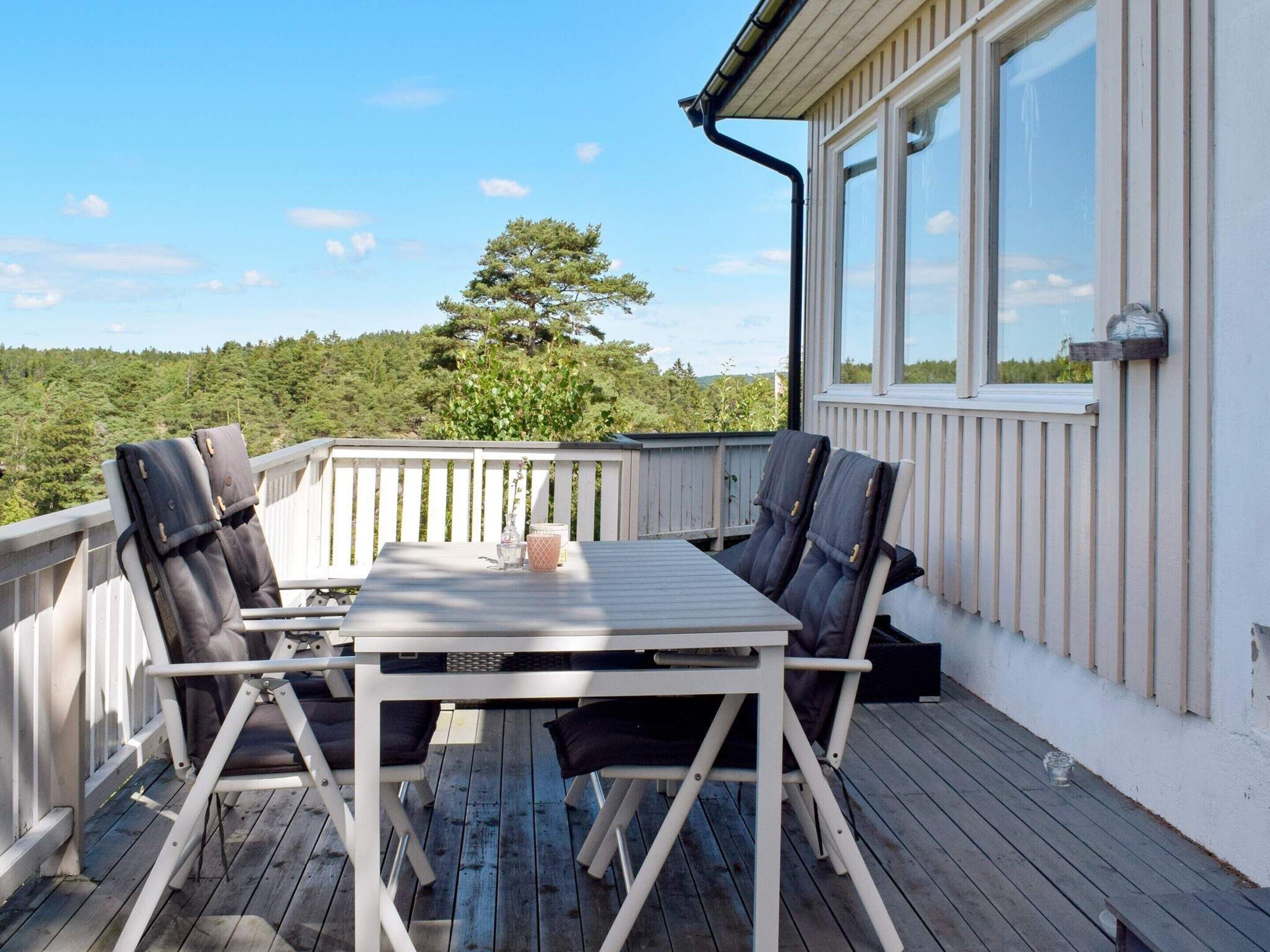 A deck with a table and chairs, overlooking a forested area.