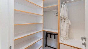 A walk-in closet with open shelves and a hanging robe. - Luxury condo within the Seven Mile Beach Corridor (Grand Cayman)