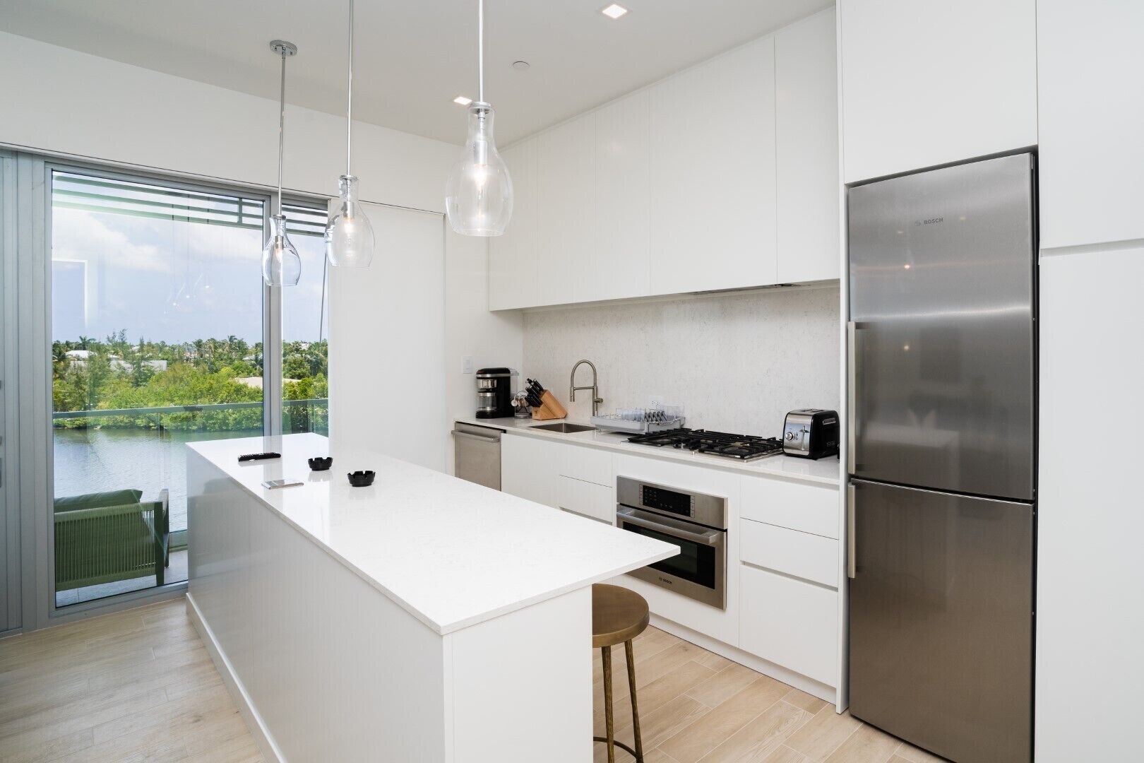 Una cocina moderna con una isla grande, electrodomésticos de acero inoxidable y vistas a un cuerpo de agua.