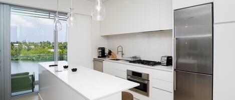 Una cocina moderna con una isla grande, electrodomésticos de acero inoxidable y vistas a un cuerpo de agua.