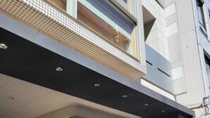 A modern building entrance with a glass facade, a metal staircase, and a sign indicating 'The ORB Luminaires Residence of the French'. - Section L Residence Ginza (Tokyo)