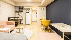 A compact living space with a kitchenette, a dining area with yellow chairs, a sofa, and a small table. - Section L Residence Ginza (Tokyo)
