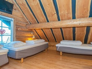 A cabin with two beds, a window with a heart decoration, and a television mounted on the wall.