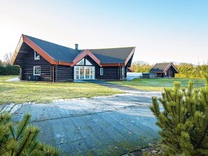 A log cabin with a sloped roof, a large glass door, and a smaller adjacent structure.