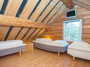 Un dormitorio acogedor en el ático con vigas de madera, un ventanal grande y dos camas.