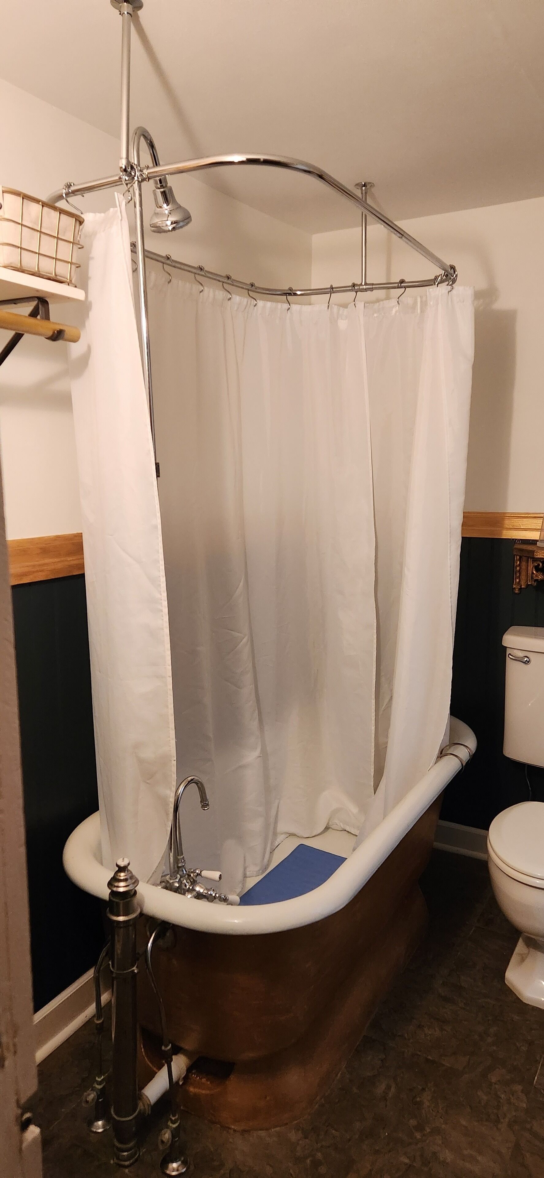 Et badeværelse med et fristående badekar, bruseforhæng, toilet og vask.
