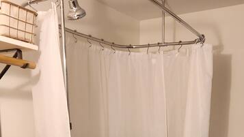 Et badeværelse med et fristående badekar, bruseforhæng, toilet og vask.
