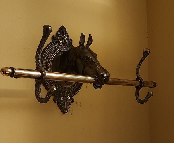 A wall-mounted metal hook with an ornate design, possibly for hanging coats or bags.