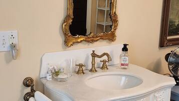 Une salle de bain avec un meuble-lavabo blanc, un miroir à cadre doré et un lavabo blanc.