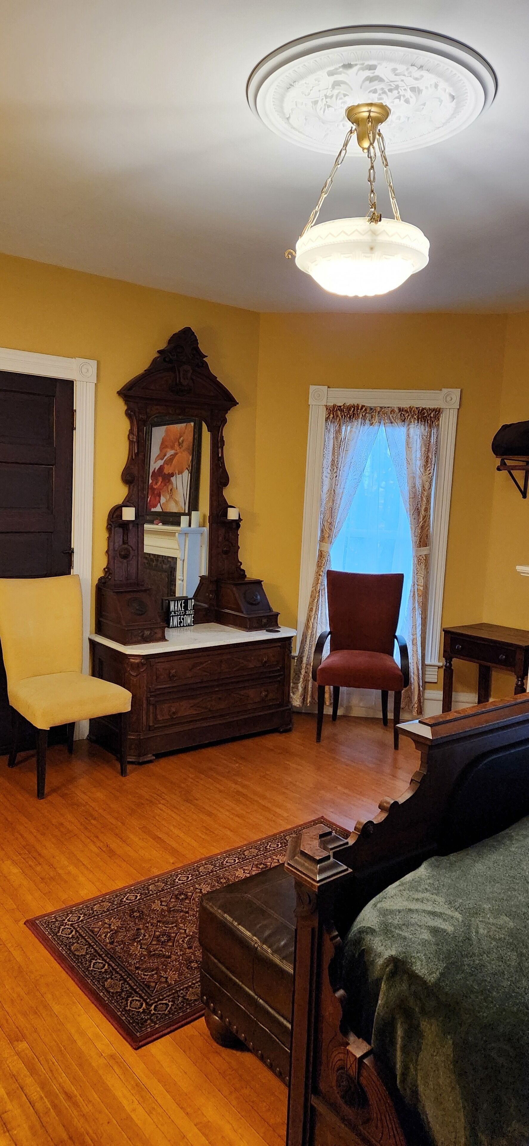 Una habitación con un aparador de madera, una silla roja, un sofá y una lámpara en el techo.