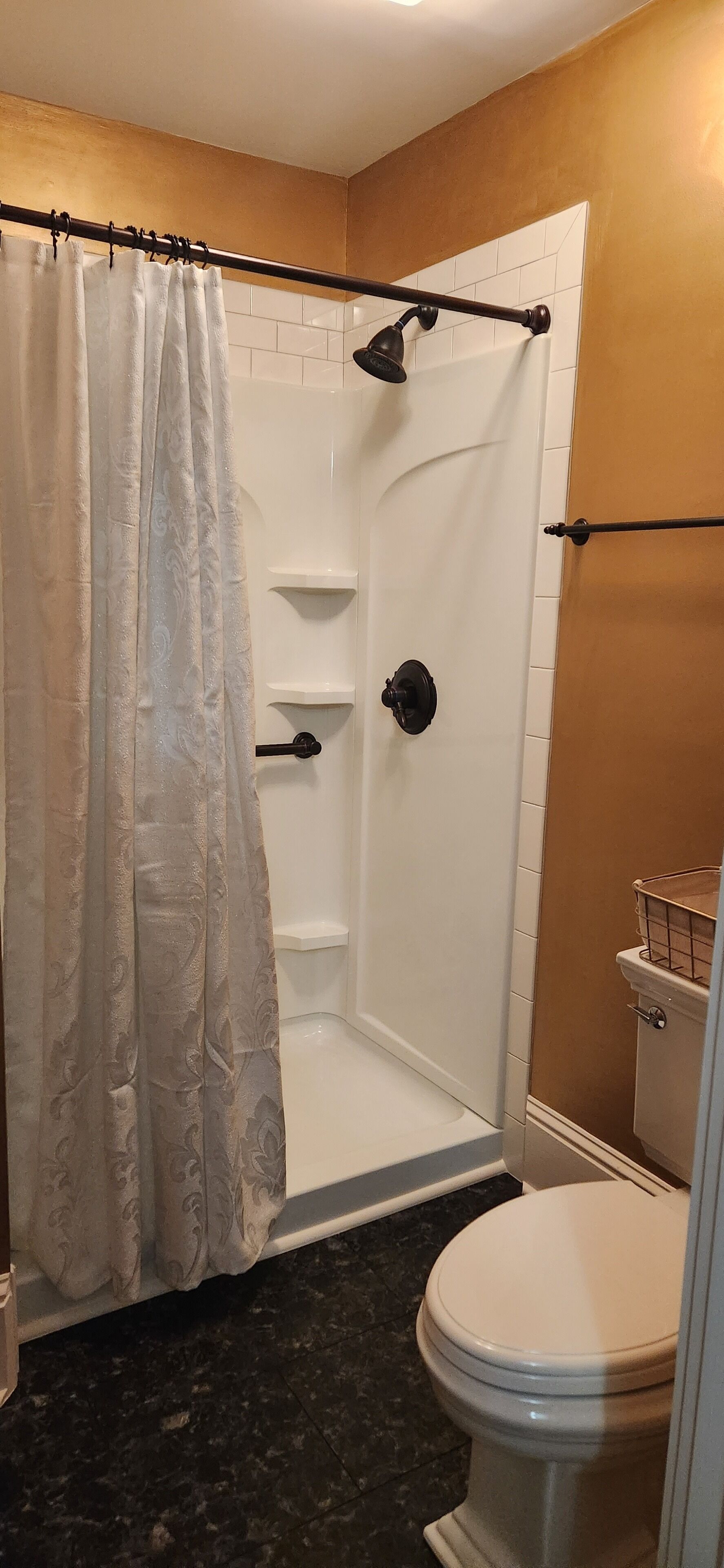 A bathroom with a shower, toilet, and a curtain.