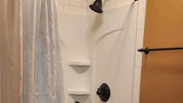 A bathroom with a shower, toilet, and a curtain.