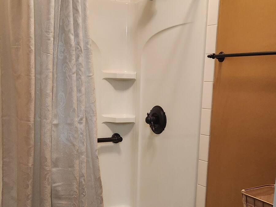 A bathroom with a shower, toilet, and a curtain.