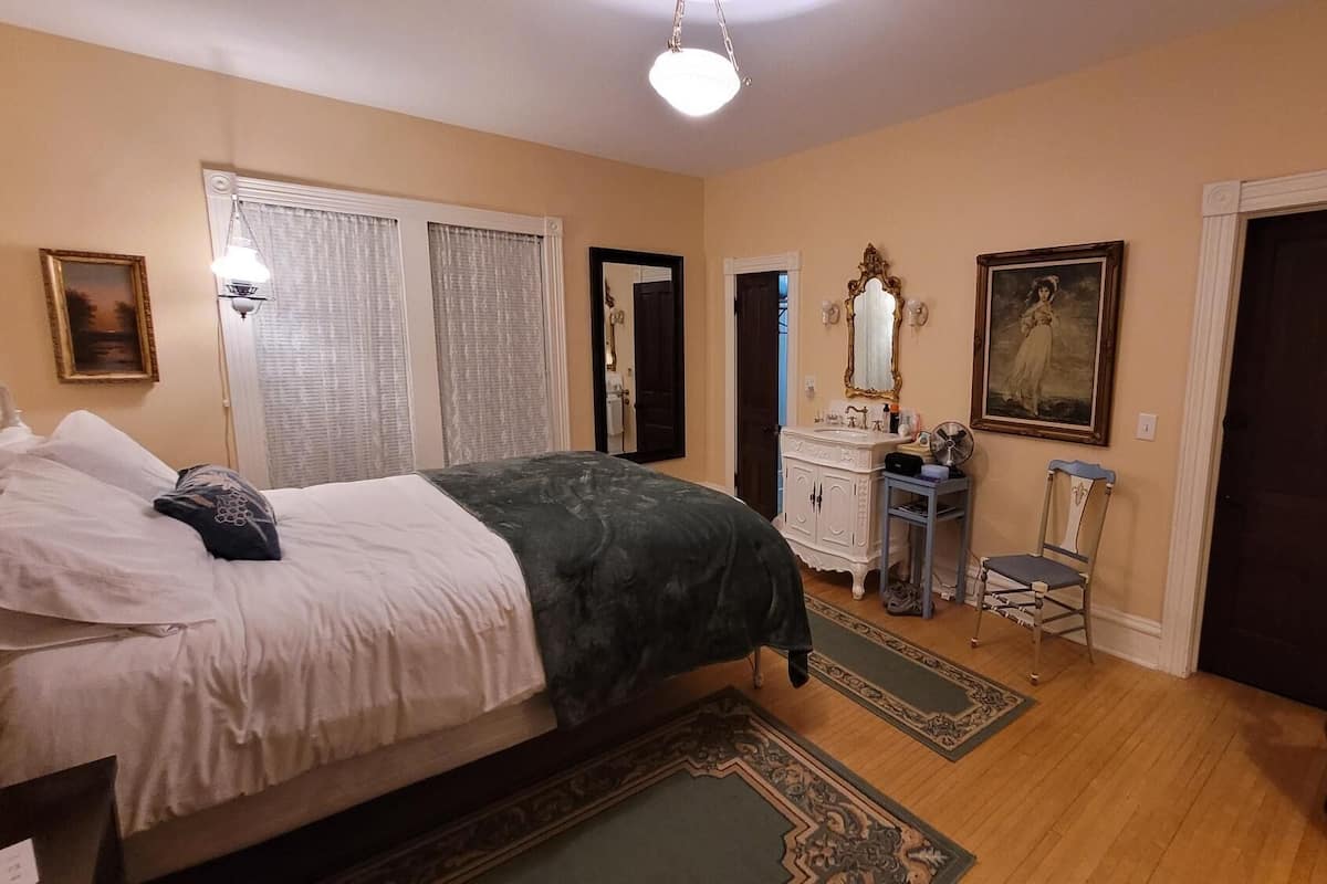 A bedroom with a bed, dresser, chair, and a door.