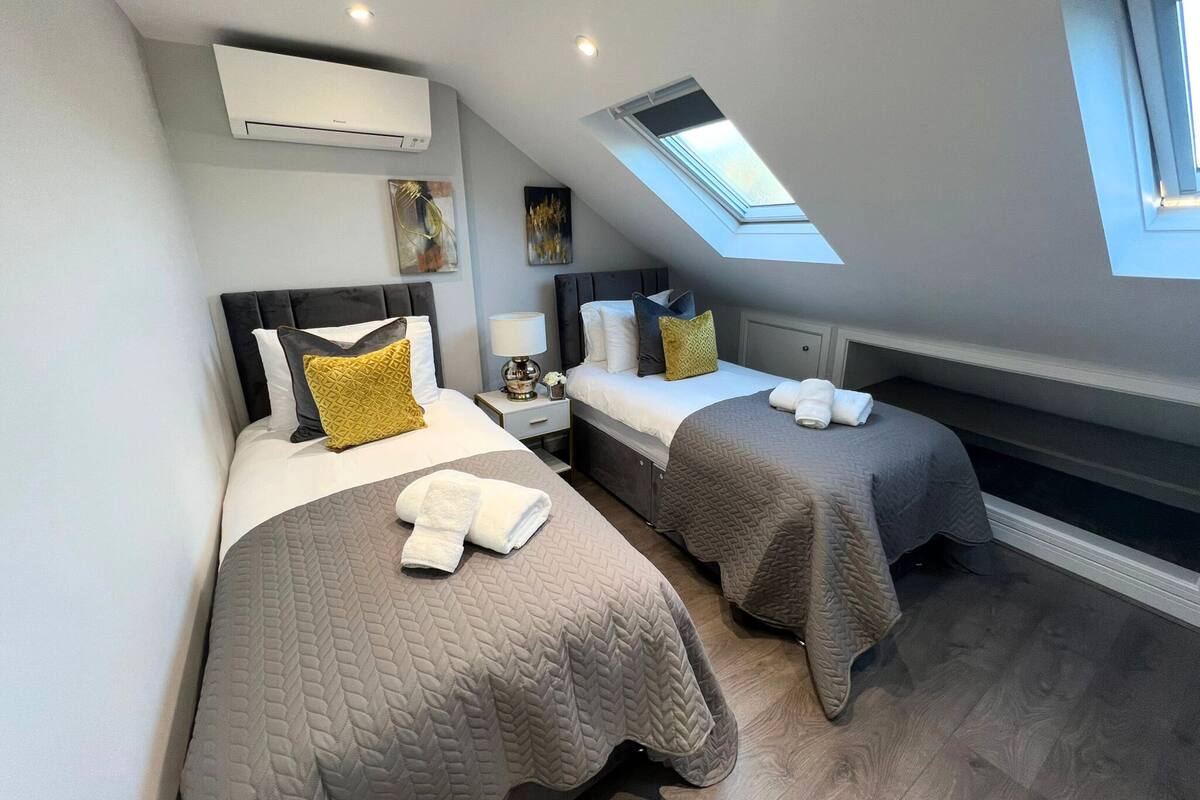 A bedroom with two beds, a skylight, and an air conditioning unit.