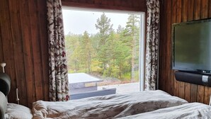 A bedroom with a bed, a television, and a window with curtains. - 6 Person Holiday Home in Halden-by Traum (Halden)