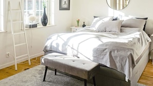 Une chambre à coucher comprenant un lit, un banc, une échelle, une fenêtre, un miroir et une étagère fixée au mur.