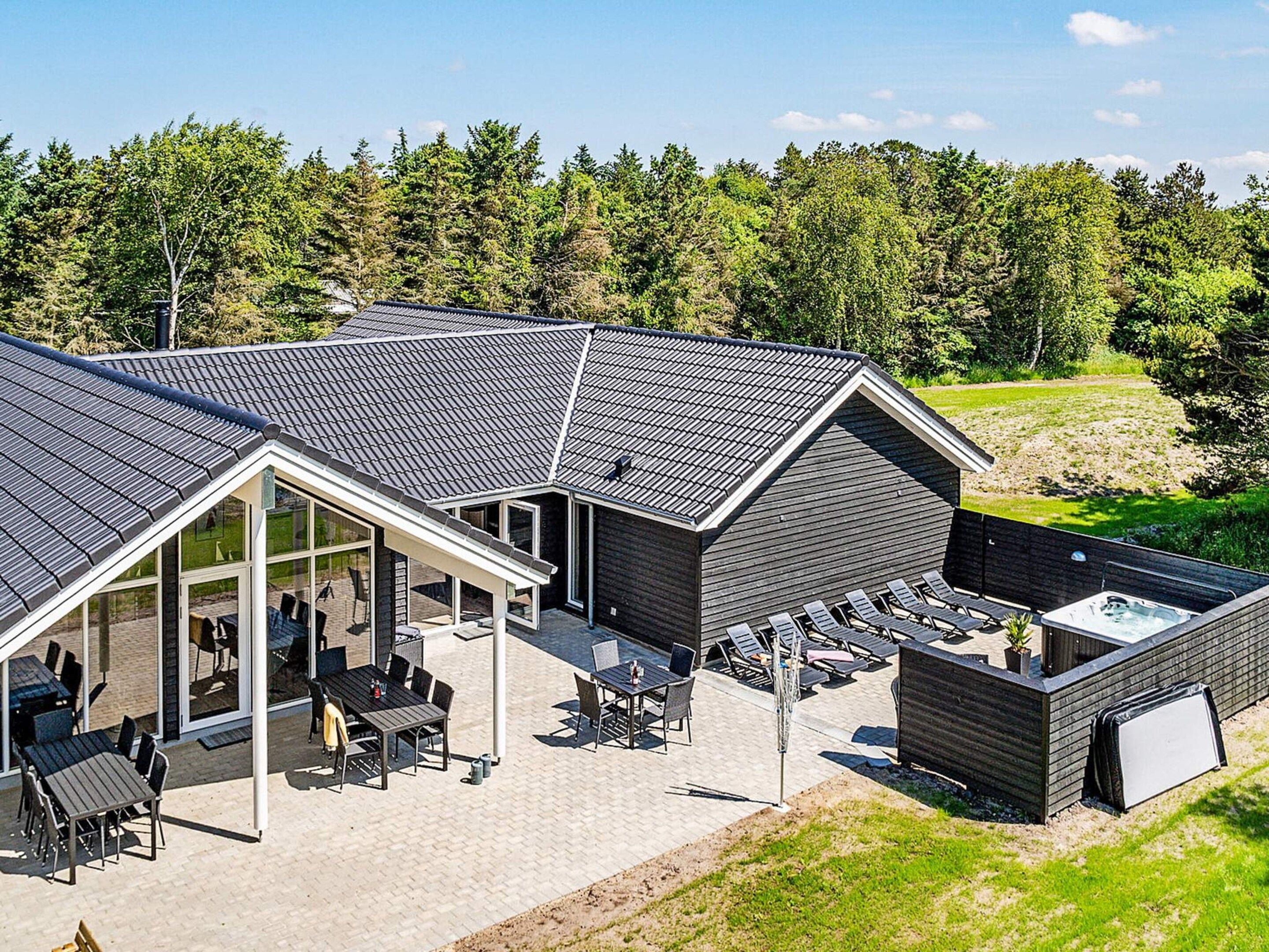 A modern building with a sloped roof, outdoor seating area, and a hot tub.