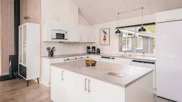 Una cocina moderna con armarios blancos, una isla central, un microondas integrado y una estufa.