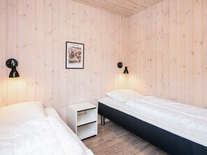 A room with two beds, a nightstand, and two wall-mounted lamps. - 5 Star Holiday Home in Blavand (Blavand)