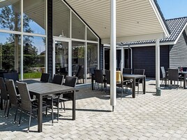 An outdoor patio area with tables and chairs, a covered seating area, and a view of the surrounding landscape.