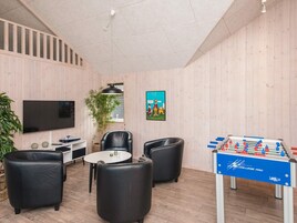 A room with a flat-screen TV, a foosball table, and a dining area with chairs and a table.
