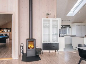 A modern living space with a wood-burning stove, a billiards table, and a kitchen area. - 5 Star Holiday Home in Blavand (Blavand)