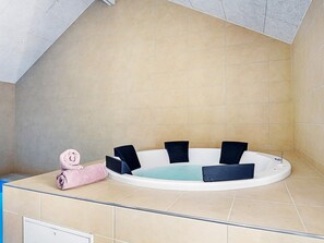A bathtub with black chairs, a pink towel, and beige tiles. - 5 Star Holiday Home in Blavand (Blavand)